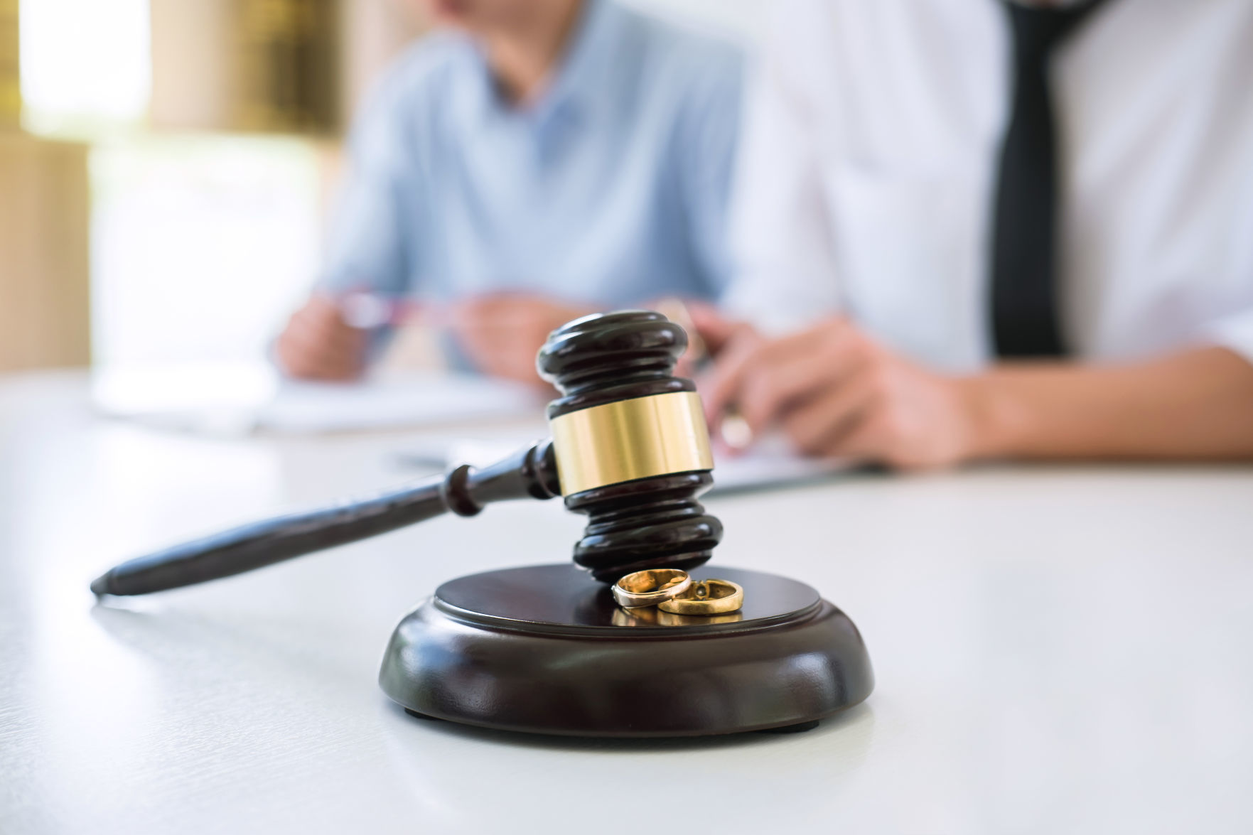 Close up of Judge gavel and two golden marriage ring, Contract decree of divorce (dissolution or cancellation) of marriage, husband and wife during divorce process and signing of divorce contract